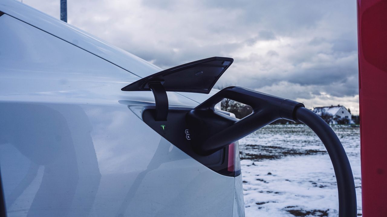 Close-up of a white electric car charging outdoors in a snowy winter landscape.